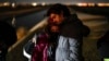 El migrante cubano Mario Pérez sostiene a su esposa mientras esperan ser procesados para solicitar asilo, luego de cruzar la frontera hacia EEUU, el 6 de enero de 2023, cerca de Yuma, Arizona. (AP/Gregory Bull)