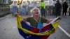 Consuelo Márquez sostiene una bandera venezolana frente a la policía que bloquea manifestaciones contra los resultados oficiales de las elecciones en Venezuela. (AP/Matías Delacroix)