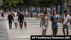 La gente camina en el Paseo del Prado mientras miembros de la policía patrullan en La Habana, Cuba, el lunes 11 de julio de 2022.