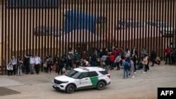 Migrantes y solicitantes de asilo esperan ser procesados por la Patrulla Fronteriza en la frontera entre Estados Unidos y México, vista desde Tijuana, estado de Baja California, México, el 5 de junio de 2024.