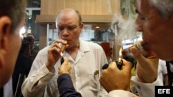El ministro cubano de Inversión Extranjera, Rodrigo Malmierca (c), enciende un puro durante la inauguración de la feria comercial del XIV Festival del Habano, en La Habana.