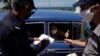 La policía revisa documentos de los pasajeros de un auto en el punto de control de Boca de Jaruco, en Mayabeque. (Alexandre Meneghini/Reuters).