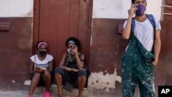 Habaneros usan máscaras por el COVID-19 afuera de una tienda de comestibles en la capital cubana, mientras esperan que abra. (AP Foto/Ramón Espinosa)