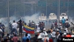 Manifestantes enfrentan los vehículos militares, cerca de la base La Carlota, en Caracas.