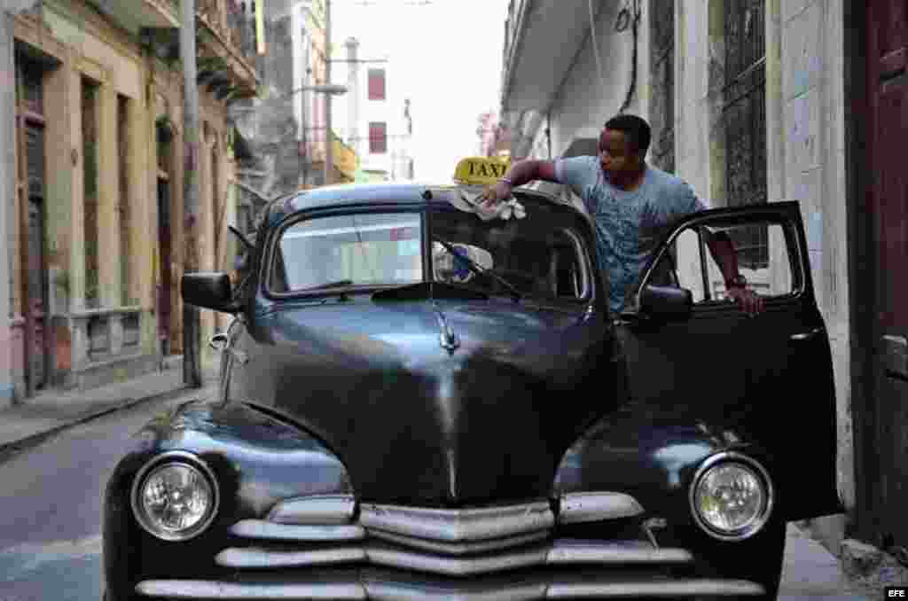 Un hombre limpia su taxi antes de iniciar labores en una calle de La Habana (Cuba), este viernes, 20 de enero de 2017, día en que Donald Trump asume la presidencia de EEUU.  