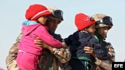 Soldados jordanos ayudan a niños sirios refugiados en la frontera noroccidental de Jordania con Siria hoy, jueves 14 de enero de 2016