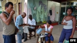 Varias personas toman café en el portal de una tienda.