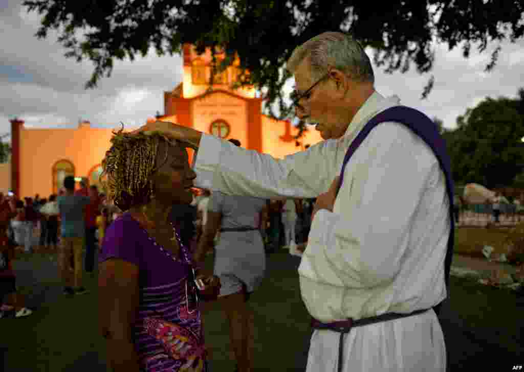 Un sacerdote bendice a un peregrino durante la procesión a El Rincón en adoración a San Lázaro. Yamil Lage/AFP