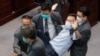 Los guardias de seguridad arrastran al legislador pro democracia Ray Chan durante una reunión legislativa el 8 de mayo en Hong Kong.