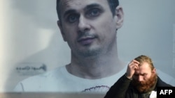 Un hombre se detiene frente a una imagen gigante del cineasta ucraniano Oleg Sentsov en una calle de Kiev.